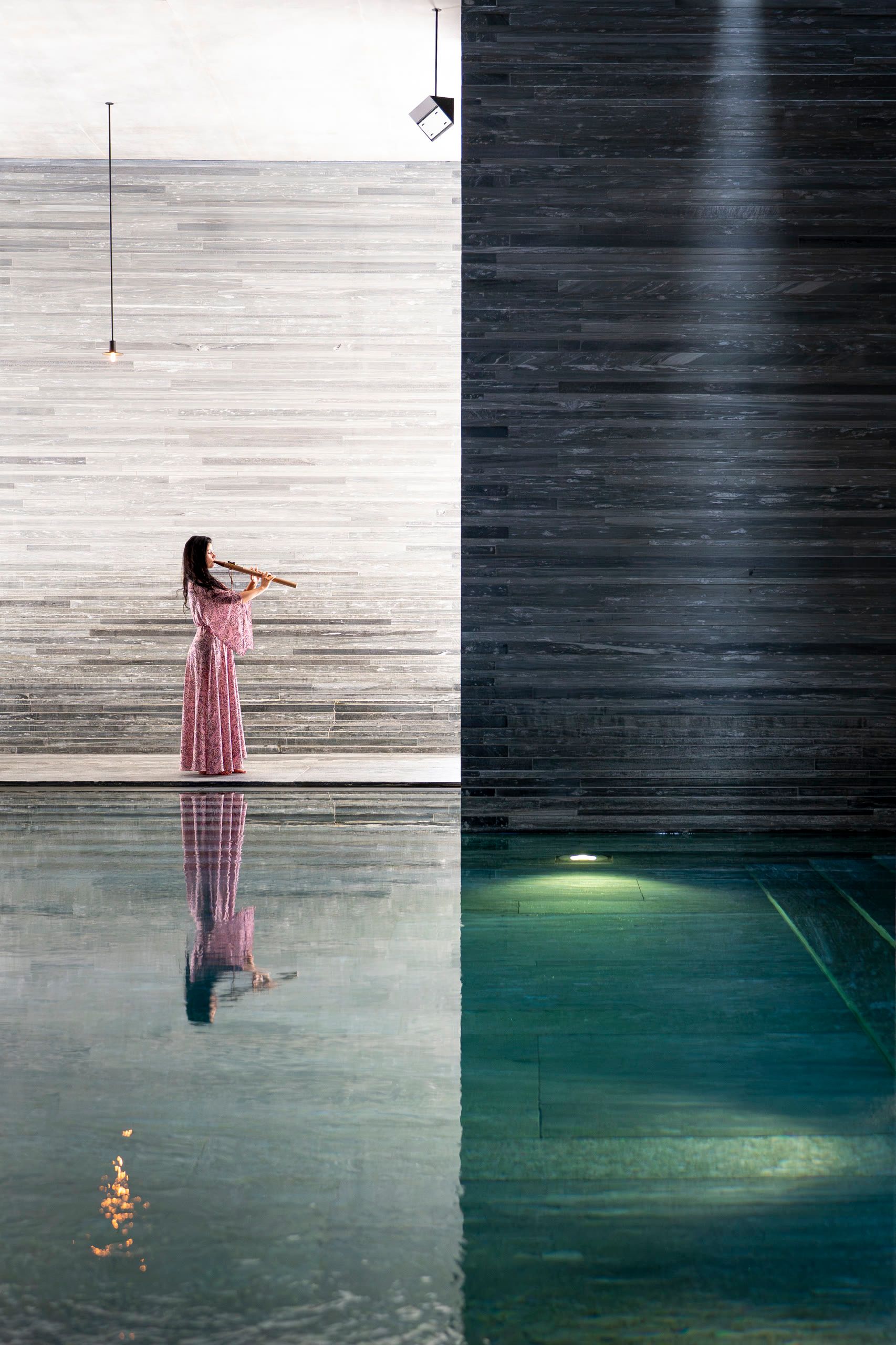 Harriet Emily playing the flute beside the stone-walled pool at 7132 Hotel