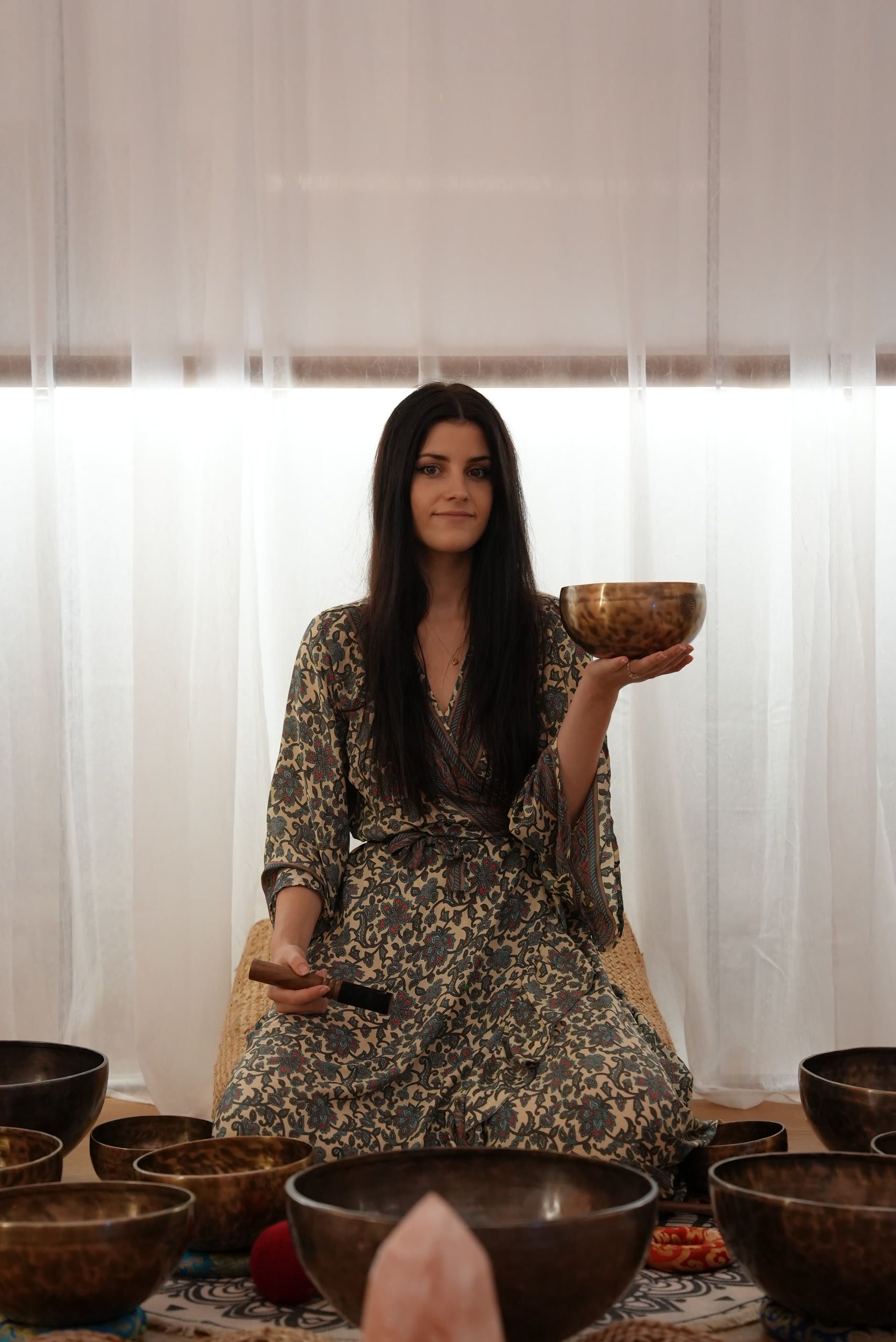 Harriet Emily holding a singing bowl, surrounded by singing bowls, at Harrods, London