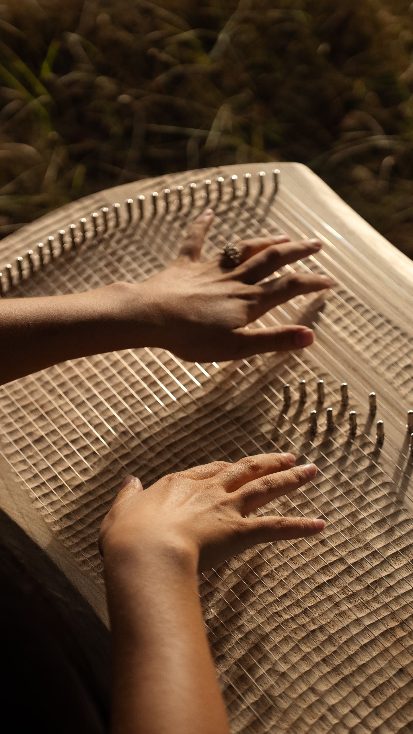 Close-up of Harriet Emily’s hands playing a wooden stringed instrument